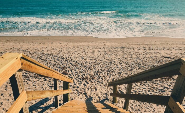 brown wooden stairs on sand by the seashore during the day in Destin in August