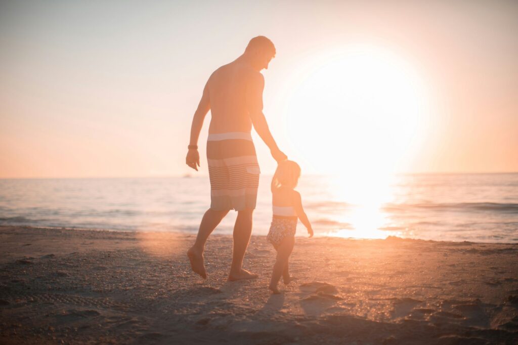 a father and son at a beach during sunset