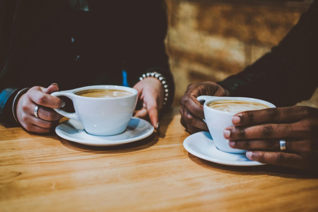 a closeup of two coffee cups on a table held by two people